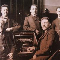 De heren van de Kas Bank te Amsterdam die trots voor hun eerste schrijfmachine zitten. 