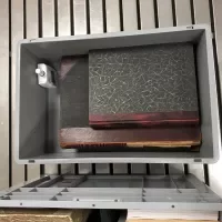 Groot formaat boeken worden liggend in een container geplaatst, met monitoring van het klimaat door een sensor in de hoek van de container.