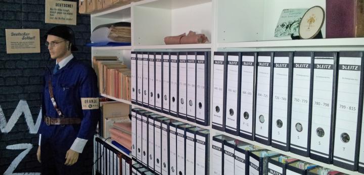 Foto van boekenkasten met multomappen en archiefdozen